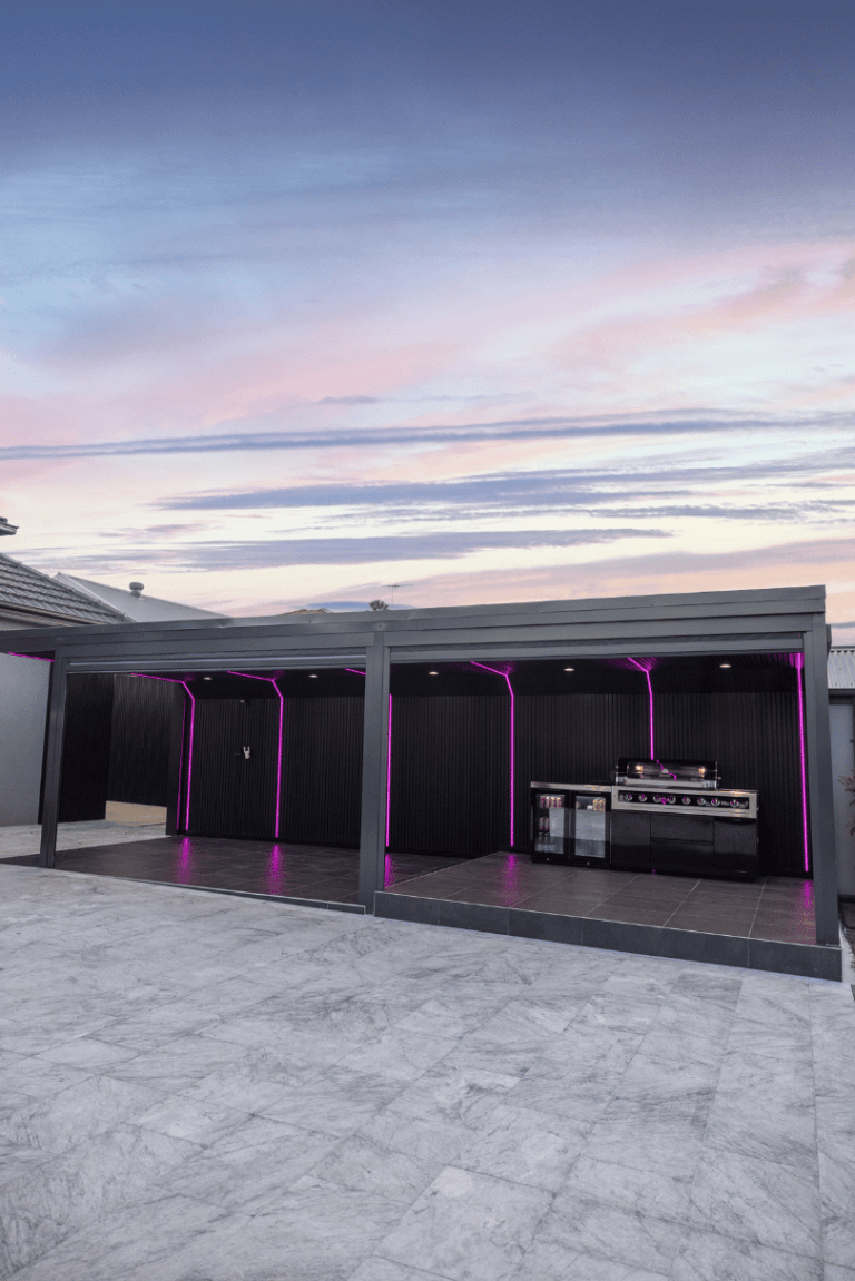 Covered outdoor entertaining area with built-in barbecue at dusk