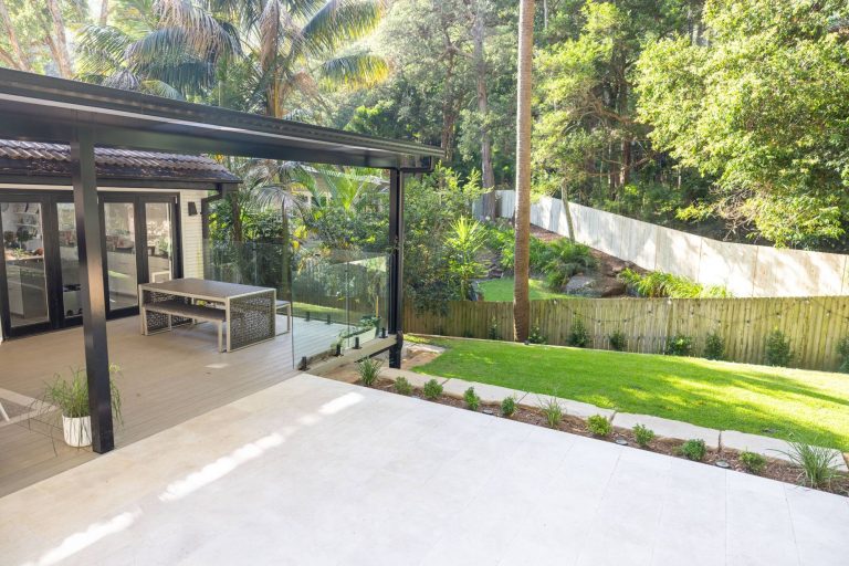 Backbeach composite deck under an insulated pergola with glass balustrade overlooking the garden in Bayview